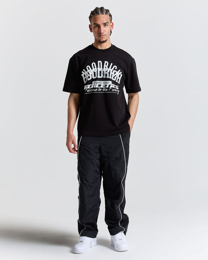 Man wearing a black t-shirt with text and black pants on a white background