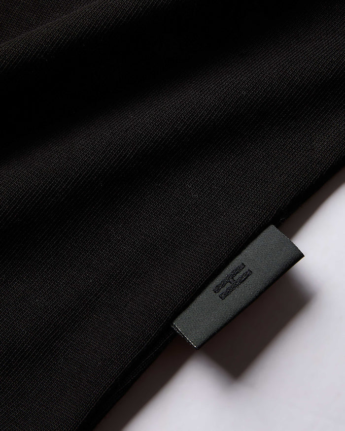 Close-up of a black garment with a brand label on a white background