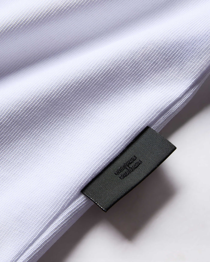Close-up of a white shirt with a black label on a light background