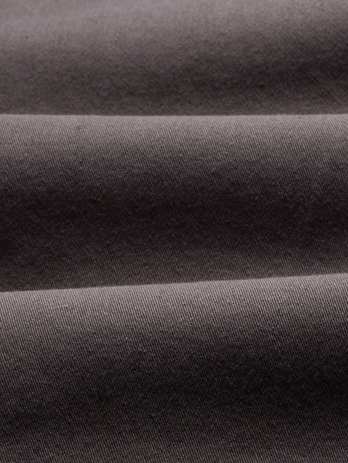 Close-up of grey twill fabric with folds, showing the pants' woven texture.
