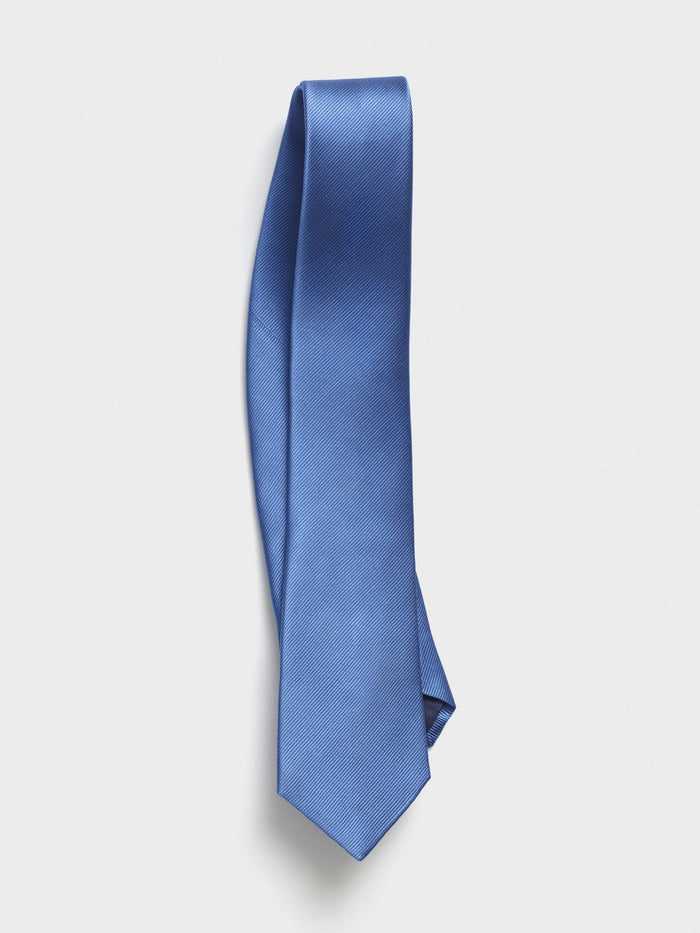 Cobalt silk necktie with twill texture, draped diagonally on a grey background.