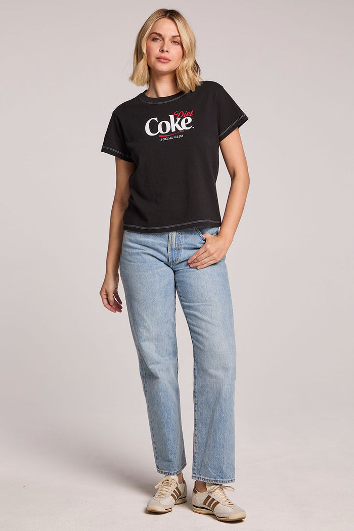 Full body front view of a woman wearing the Chaser Coca Cola Diet Coke Tee and sneakers on a neutral background