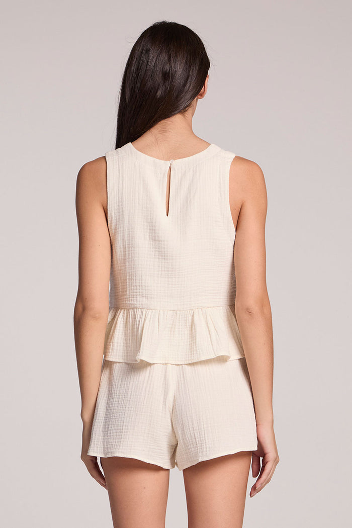 Back view of a woman in a matching tank and shorts set on a neutral background