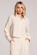 Front view of a woman wearing the Chaser Paso Crop Button Up on a neutral background