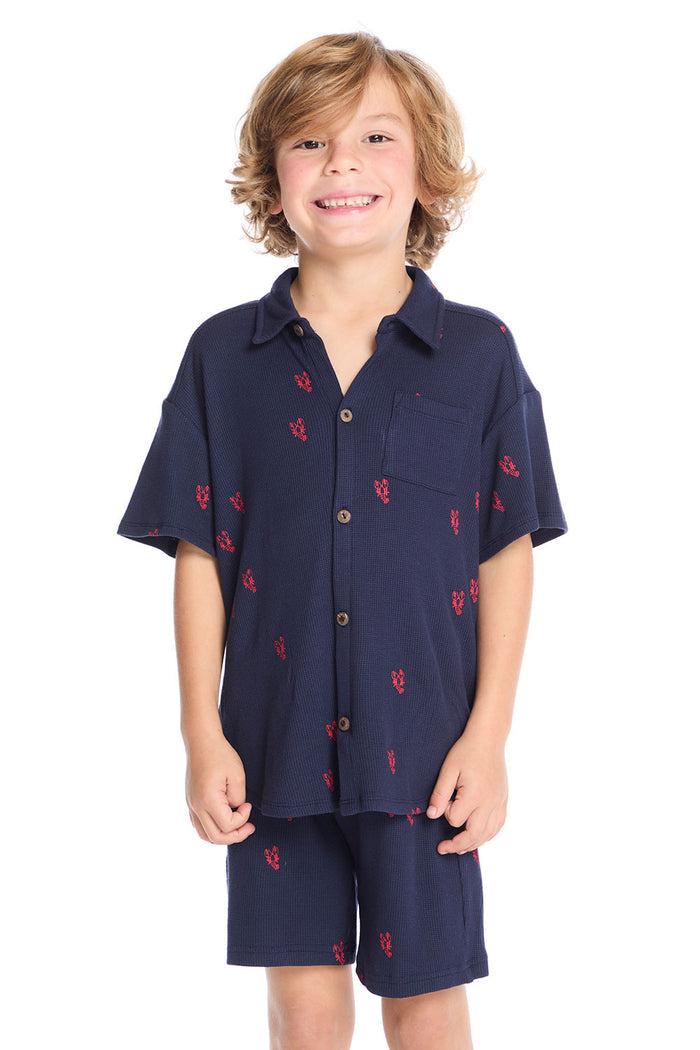 Front view of boy wearing the Chaser Kids Collared Avalon Lobsters Shirt in navy blue with red embroidered lobster motifs, paired with matching Avalon Lobsters Cozy Beach Shorts on a white background
