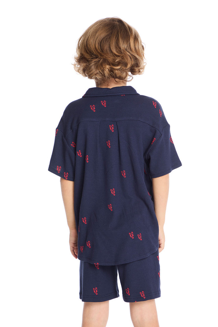 Back view of boy wearing the Chaser Kids Collared Avalon Lobsters Shirt featuring allover red lobster embroidery and straight hem, paired with matching Avalon Lobsters Cozy Beach Shorts on a white background