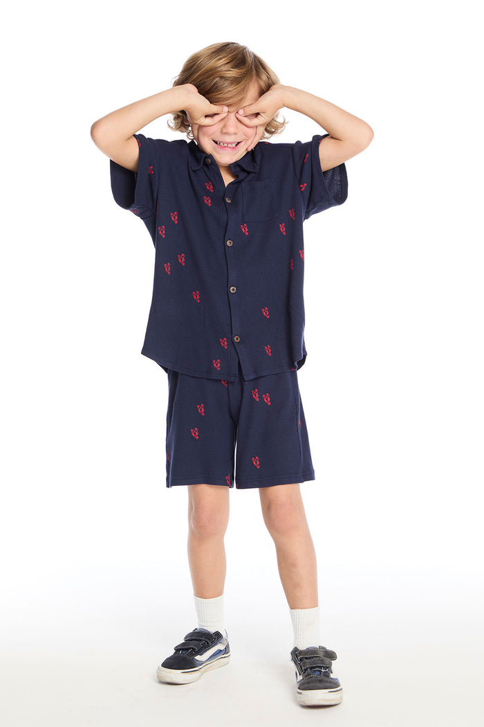 Full body view of boy wearing the Chaser Kids Collared Avalon Lobsters Shirt and matching Avalon Lobsters Cozy Beach Shorts styled with white crew socks and navy sneakers on a white background