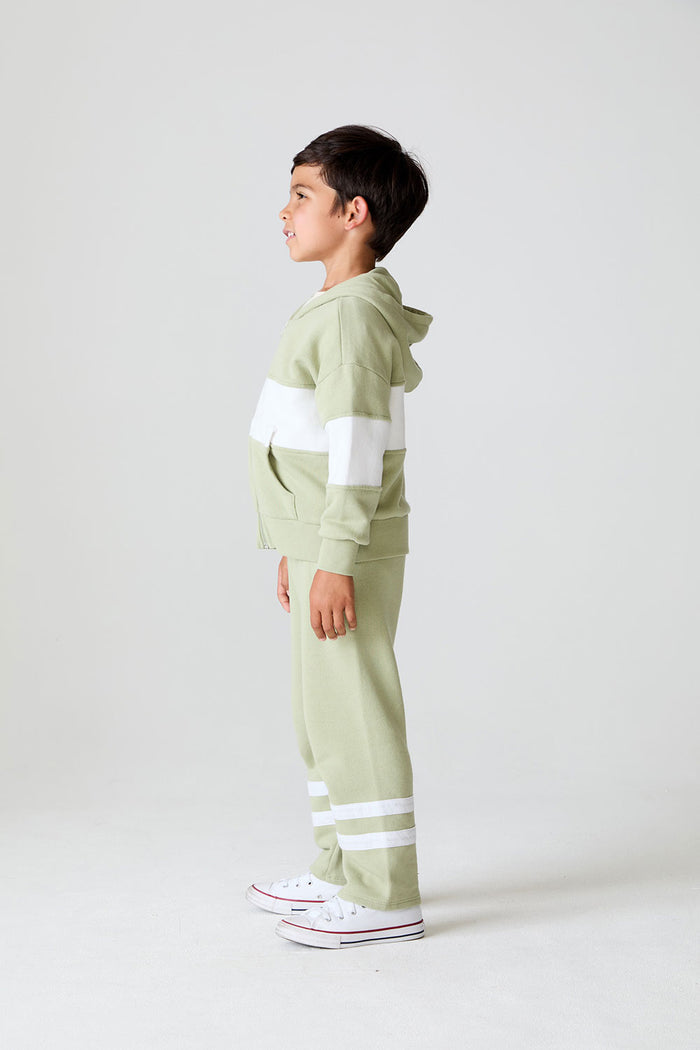 Side view of a boy wearing the Chaser Color Block Paxton Zip Up Hoodie and pants on a neutral background