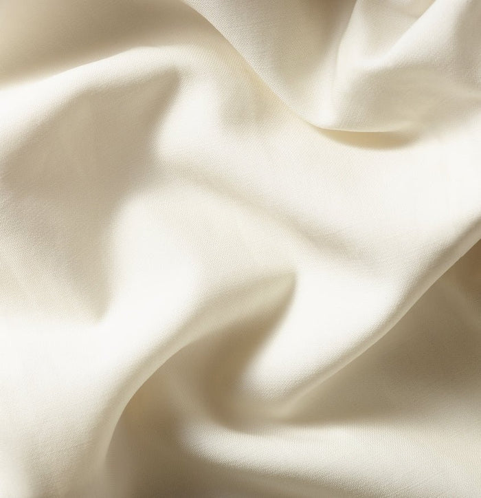 Close-up of draped ivory tuxedo jacket fabric showing soft folds.