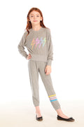 Full body view of girl wearing Chaser’s Heather Grey Contrast Strappings Pants with colorful accents on the left leg and Rainbow Bolts pullover on a white background