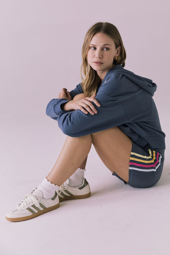 Model sitting in the Chaser Contrast Strappings Shorts and matching Contrast Strappings Zip Up Hoodie for a casual, sporty look