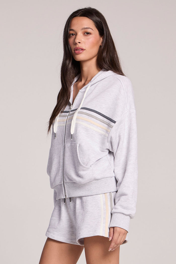 Side angle view of a woman wearing the Chaser Contrast Strappings Zip-Up set on a neutral background
