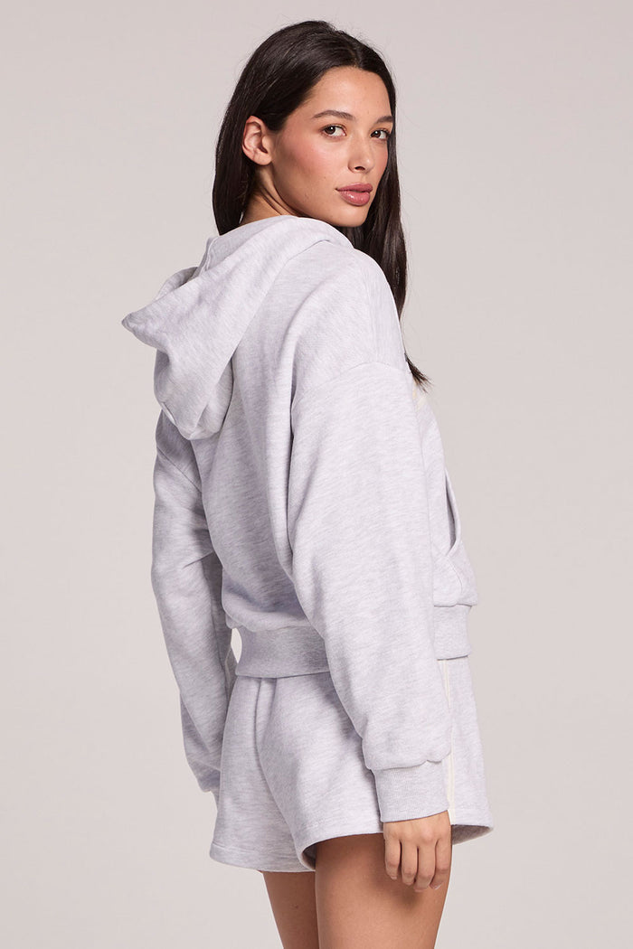 Back view of a woman wearing the Chaser Contrast Strappings Zip-Up on a neutral background