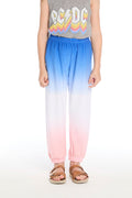 Girl wearing the Chaser Kids Cotton Candy Dip Dye Pants featuring pink, white, and blue gradient and elastic cuffs on a white background