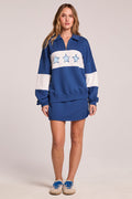 Full body front view of a woman wearing the Chaser  Courtside Skort and matching top on a neutral background