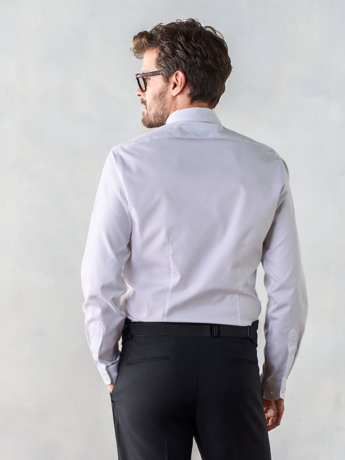 Back view of a man in a white tuxedo shirt, black cummerbund buckle visible at the waist.