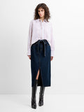 Woman wearing a high waisted, dark blue denim mid skirt with a self tie belted waist and a front slit