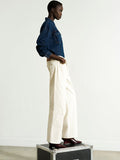 Woman wearing a dark blue denim shirt with high waisted, straight leg, clean waist jeans in ecru cream
