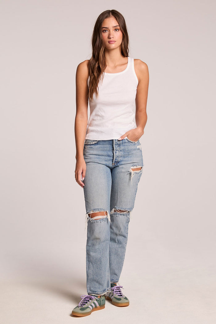 Front view of a woman wearing the Chaser    Daphne White Tank Top and sneakers on a neutral background