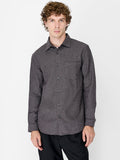 A man wearing a dark grey herringbone texture Shirt with long sleeves, a pointed collar, a chest pocket, a button through fastening and a regular fit.