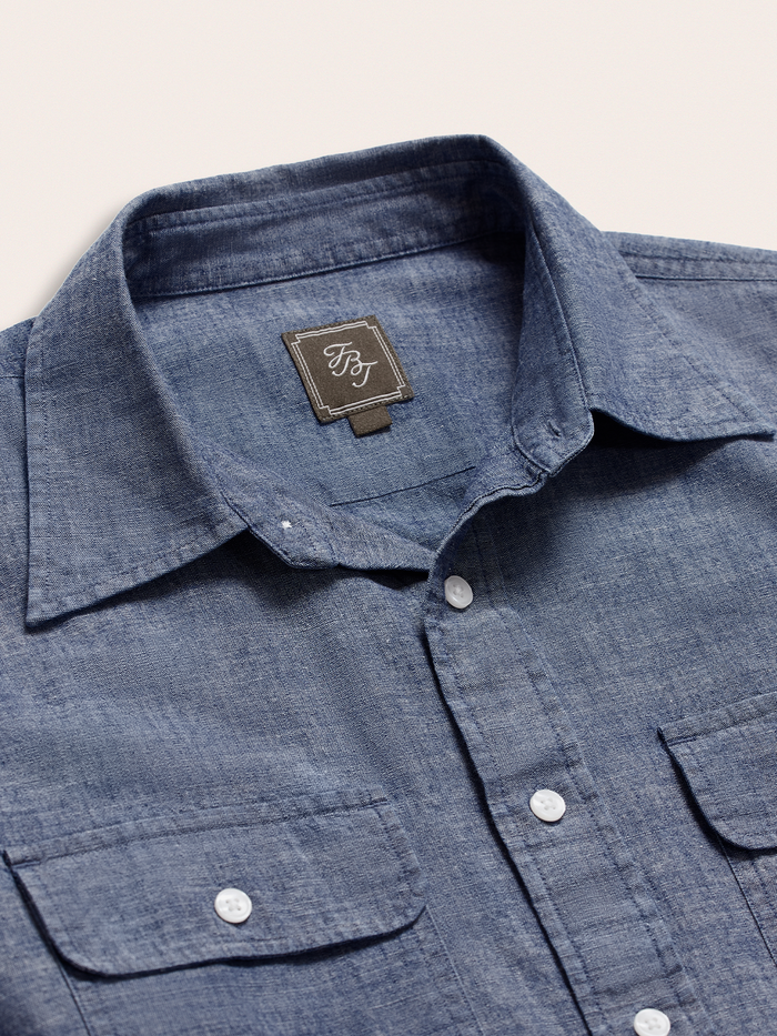 Close-up of dark wash chambray shirt collar, placket, and brand label.