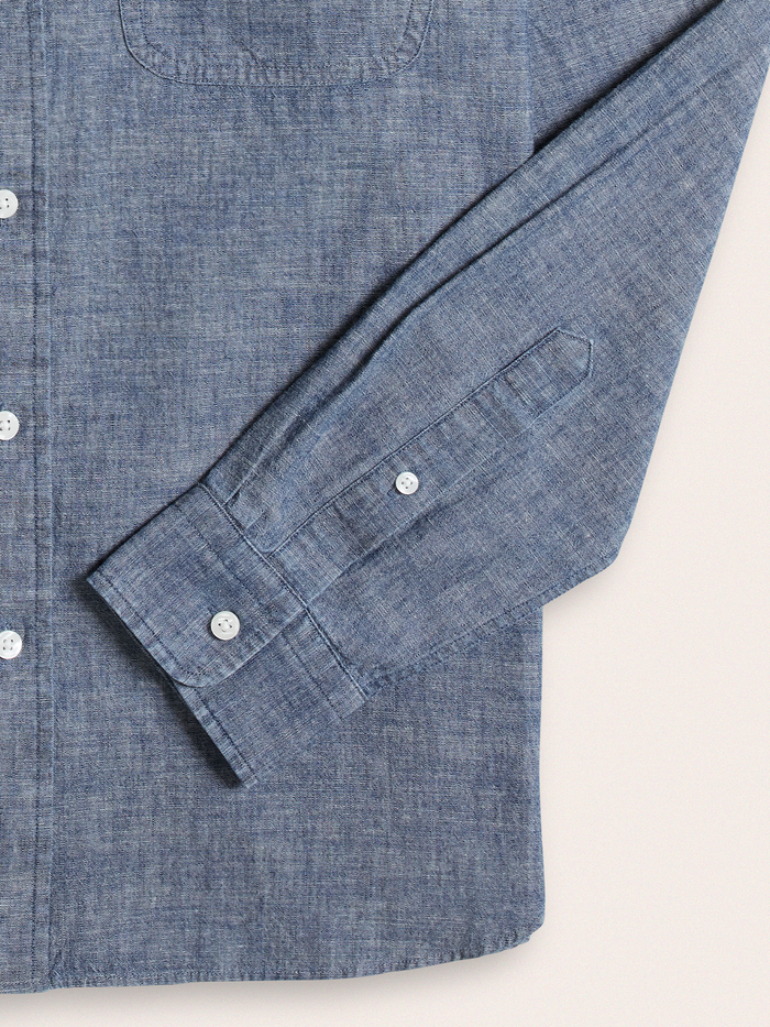 Close-up of dark wash chambray shirt cuff with button closure.