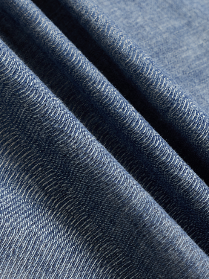 Close-up of dark wash chambray fabric showing its woven texture.