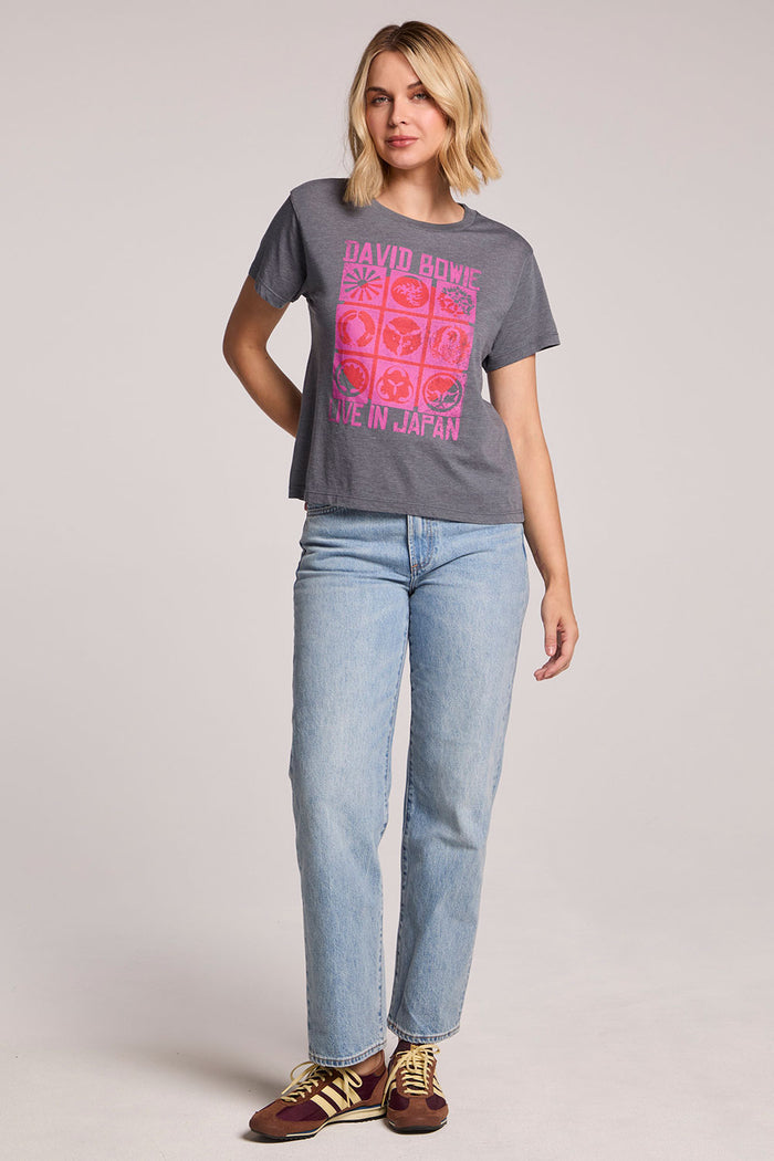 Front view of a woman wearing the Chaser David Bowie Live in Japan Tee and jeans on a neutral background