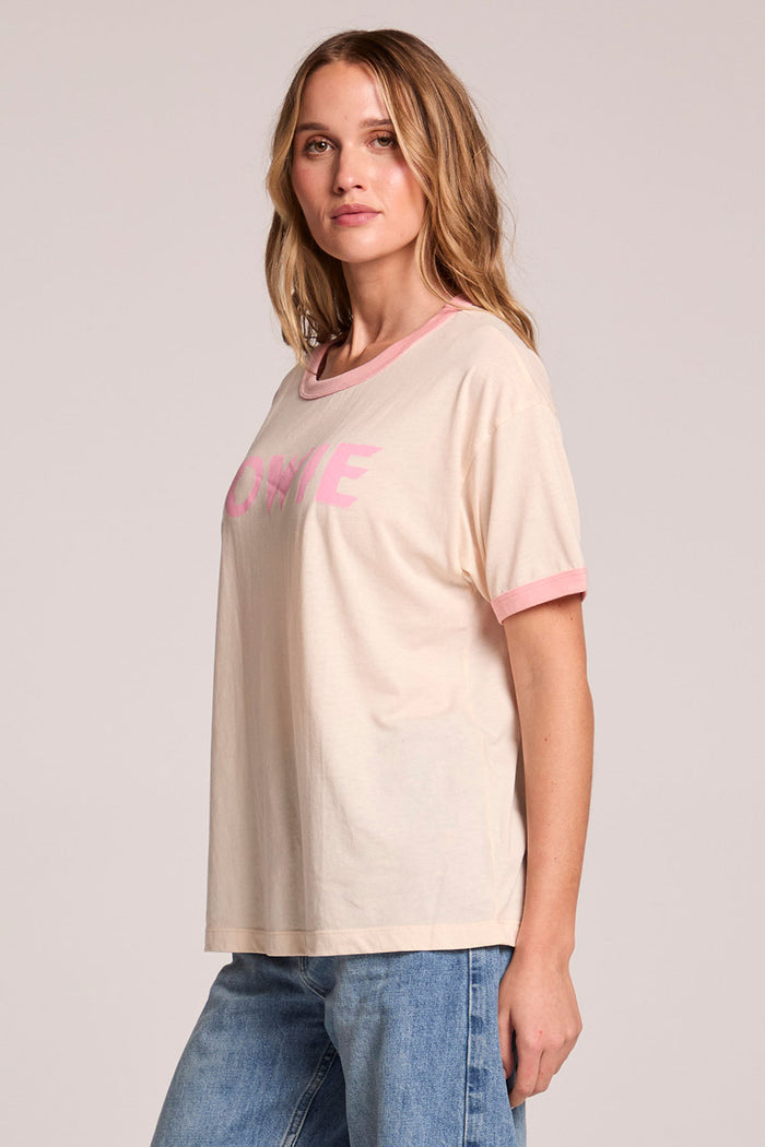 Side angle view of a woman wearing the Chaser  David Bowie Santa Monica '72 Tee on a neutral background with arms at her side
