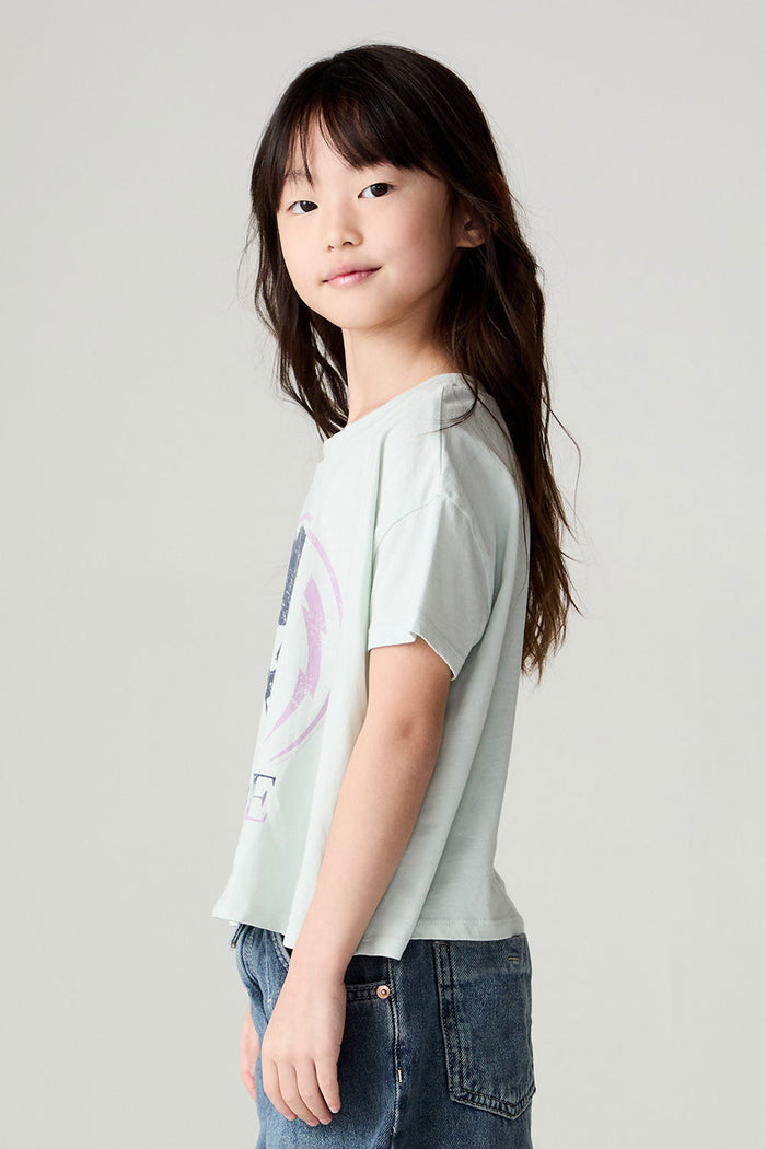 Side view of a girl wearing the Chaser David Bowie Stars Bowie Girls Tee on a neutral background with bluejeans