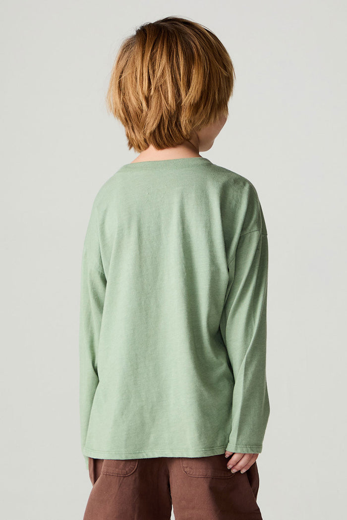 Back view of a boy wearing the Chaser Dino Action Boys Tee on a neutral background with brown pants