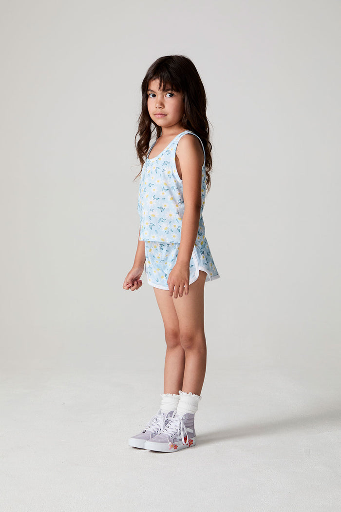 Full body side view of a girl wearing the Chaser Ditsy Daisies Tank and matching shorts on a neutral background
