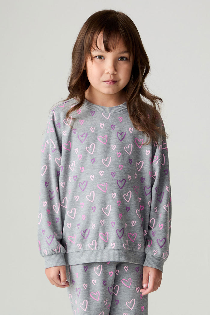 Front view of a girl wearing the Chaser Ditsy Hearts Girls Tee and matching pants on a neutral background with hands down