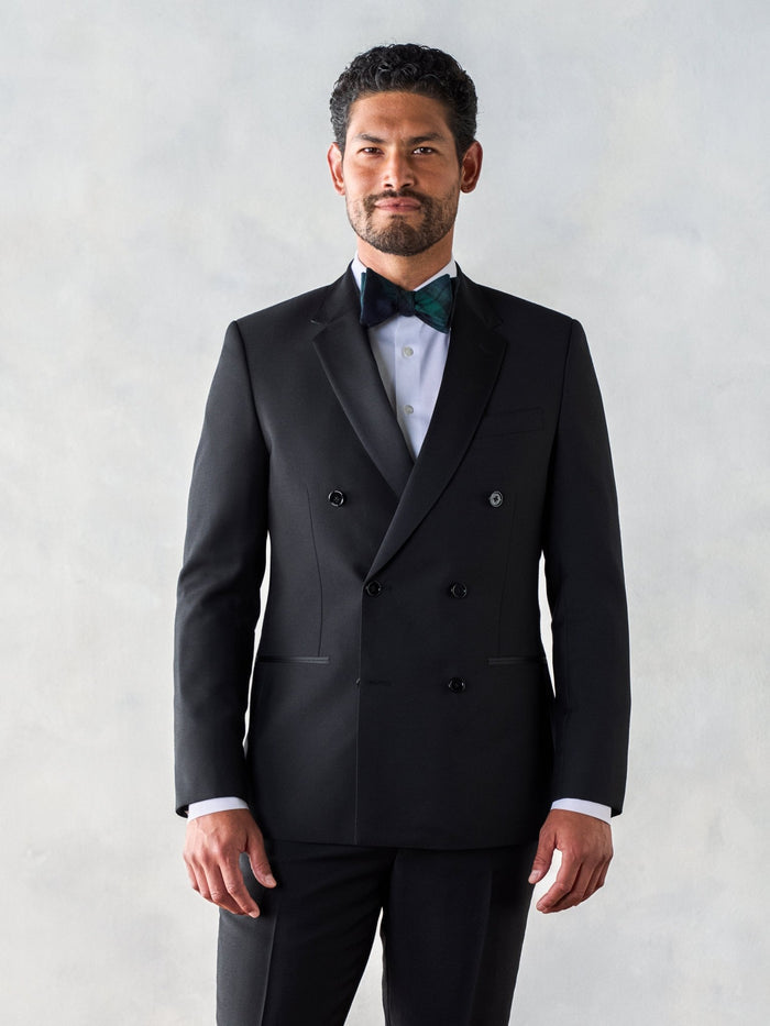 Man in a black double-breasted tuxedo jacket with peak lapels and a patterned bow tie.