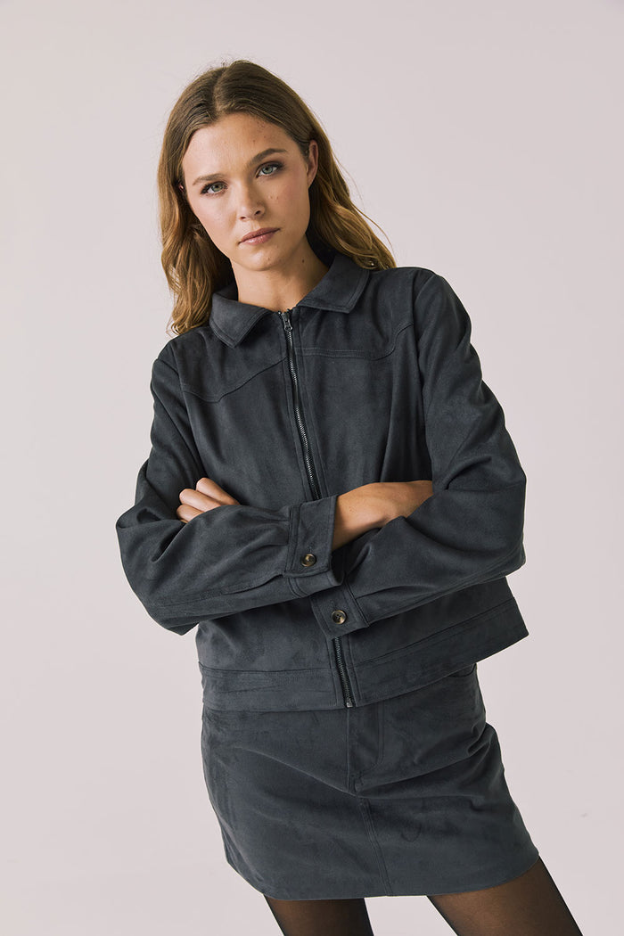 Front view of woman wearing Chaser’s Dusk True Black Jacket on a light background