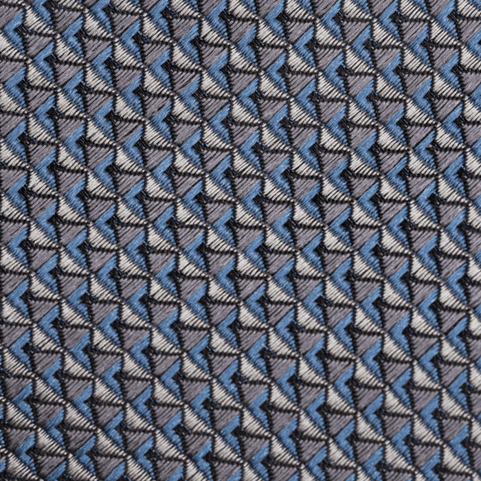 Close-up of dusty blue and grey necktie fabric with a geometric triangle weave pattern.