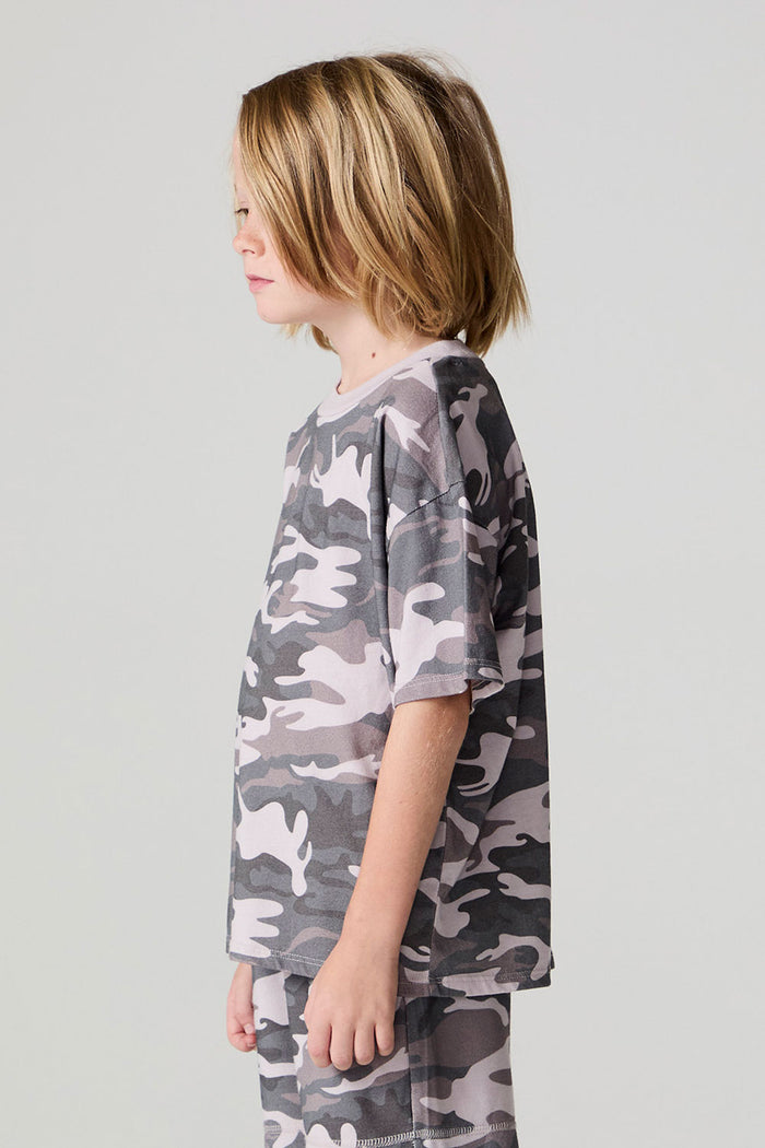 Side view of a boy wearing the Chaser Dusty Camo Tee  on a neutral background