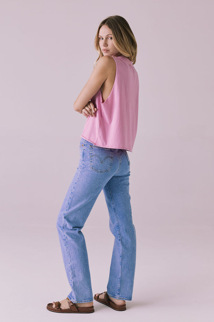 Full-length side angle of the Chaser Eagle Bubblegum Tank styled with high-rise blue jeans and brown sandals, showing the relaxed fit and casual silhouette from profile