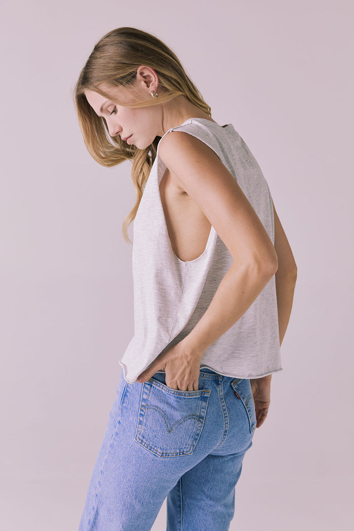 Side-back angle of the Chaser Eagle Light Heather Grey Tank tucked into jeans, emphasizing the flowy hemline and open arm design