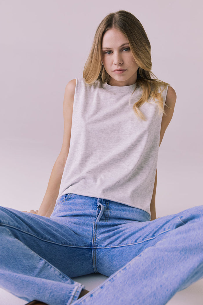 Seated pose featuring the Chaser Eagle Light Heather Grey Tank styled casually with jeans for a laid-back weekend look