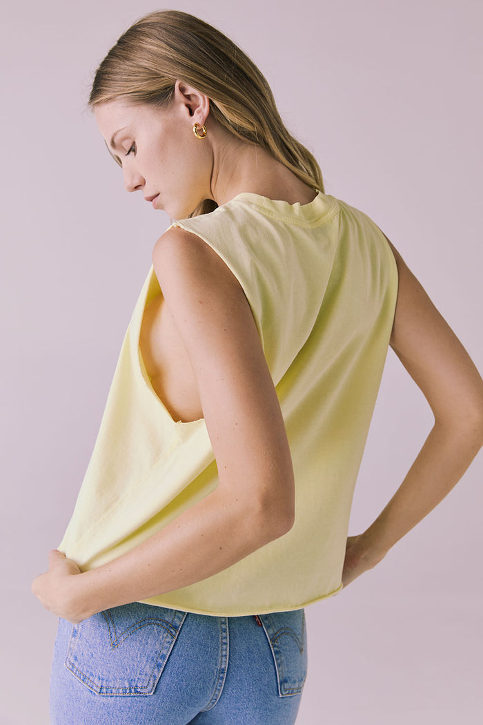 Side-back angle of the Chaser Eagle Panna Cotta Tank tucked into denim, emphasizing relaxed structure and movement