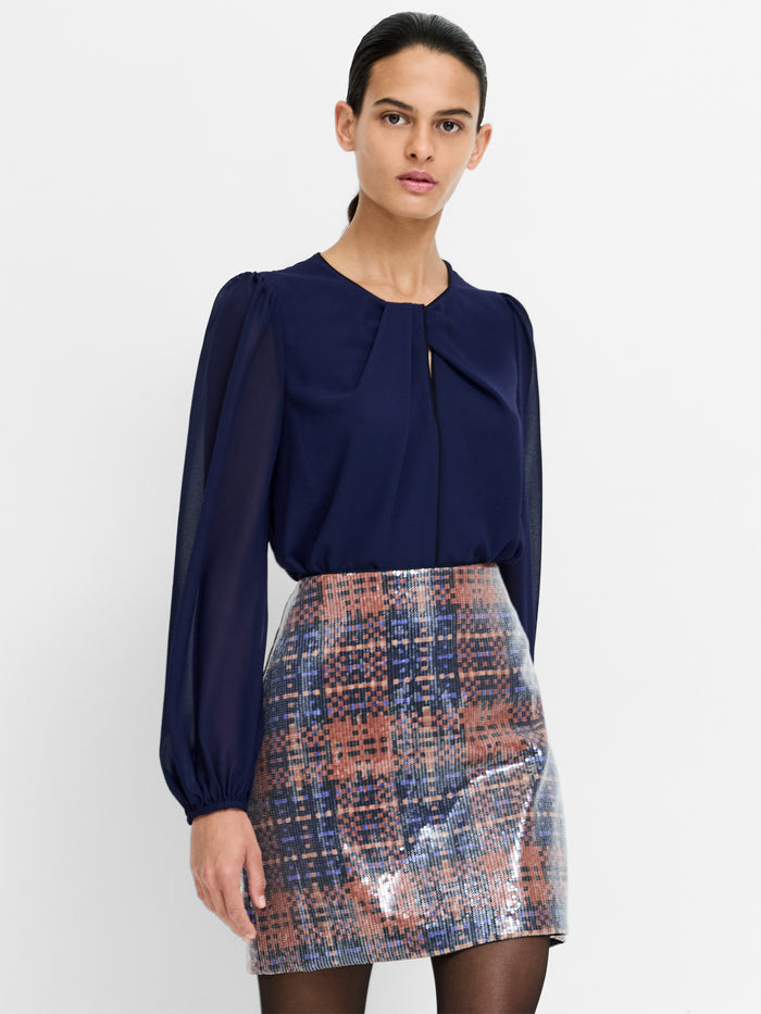 A woman wearing a semi sheer navy blue Blouse with long sleeves, a twist keyhole neckline, a back button fastening and a relaxed fit.