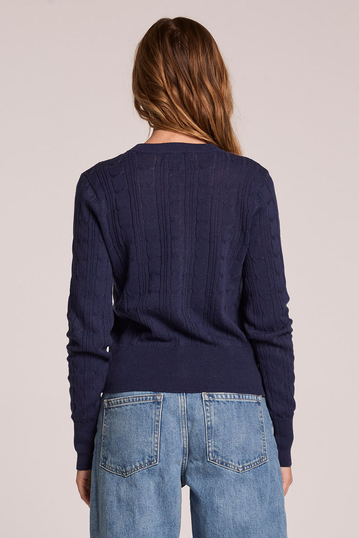 Back view of a woman wearing the Chaser  Eliza Admiral Cardigan on a neutral background