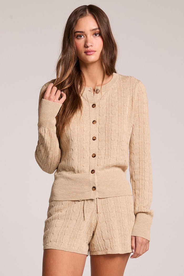 Front view of a woman wearing the Chaser Eliza Khaki Cardigan and shorts on a neutral background with one hand up