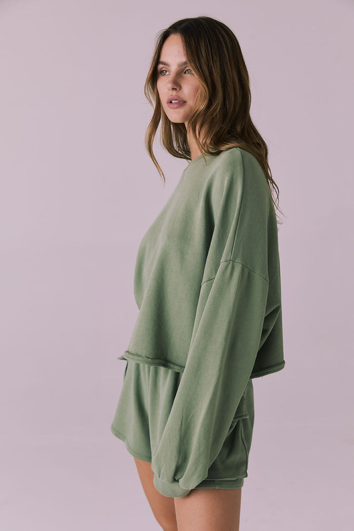 Side angle of the Chaser Eliza Meadow Green Crop Pullover highlighting the soft drop-shoulder design and slouchy sleeve shape