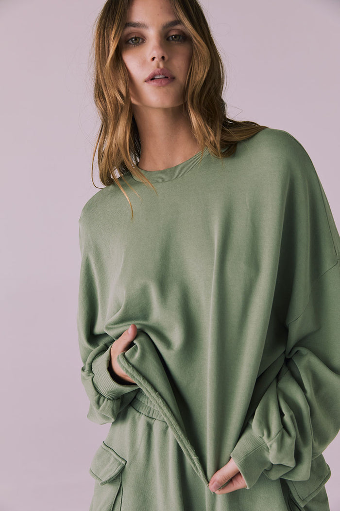 Close-up of the Chaser Eliza Meadow Green Crop Pullover focusing on the smooth cotton texture and lightly frayed edge finish