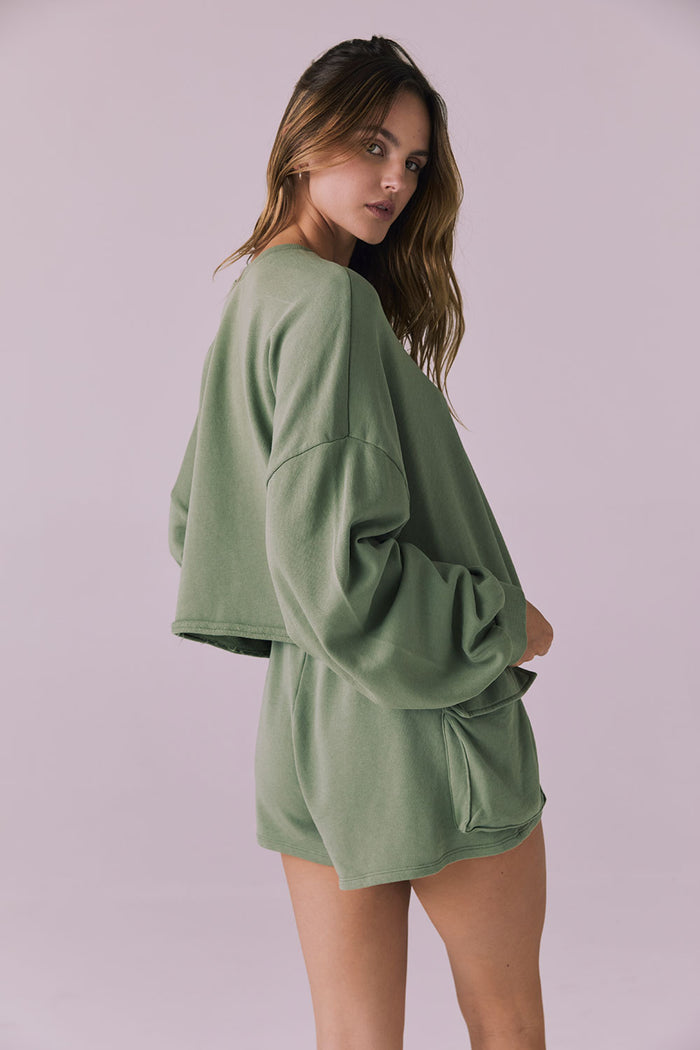 Side-back pose of the Chaser Eliza Meadow Green Crop Pullover showing the relaxed cropped length and oversized sleeve volume