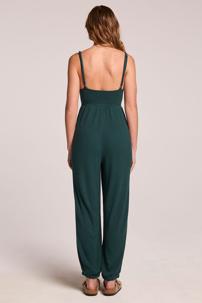 Back view of a woman wearing the Chaser  Ellery Pine Green Jumpsuit on a neutral background