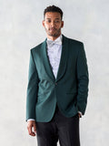 Man in an emerald green shawl-lapel tuxedo jacket with a patterned bow tie and black trousers.