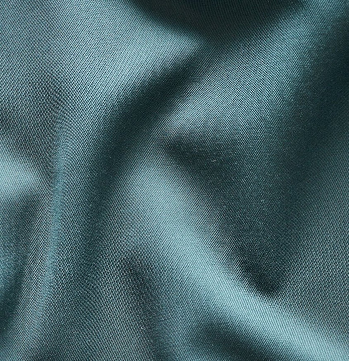 Close-up of emerald green tuxedo jacket fabric showing soft folds and sheen.